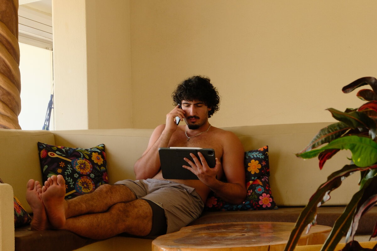 Taking the morning call from the terrace shade — feet up on the bench, tablet in hand