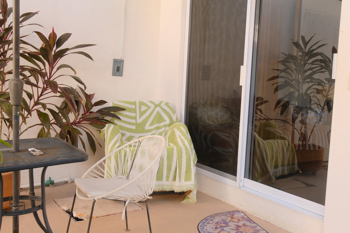 Casa Keiki living corner — rattan chair and potted plants beside the garden-level doorway