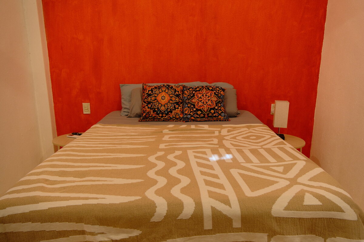 Casa Keiki bedroom — patterned bedspread against a warm accent wall with framed art