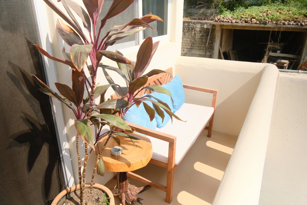 Casa Linda balcony nook — a leafy plant and seat by the sunlit window