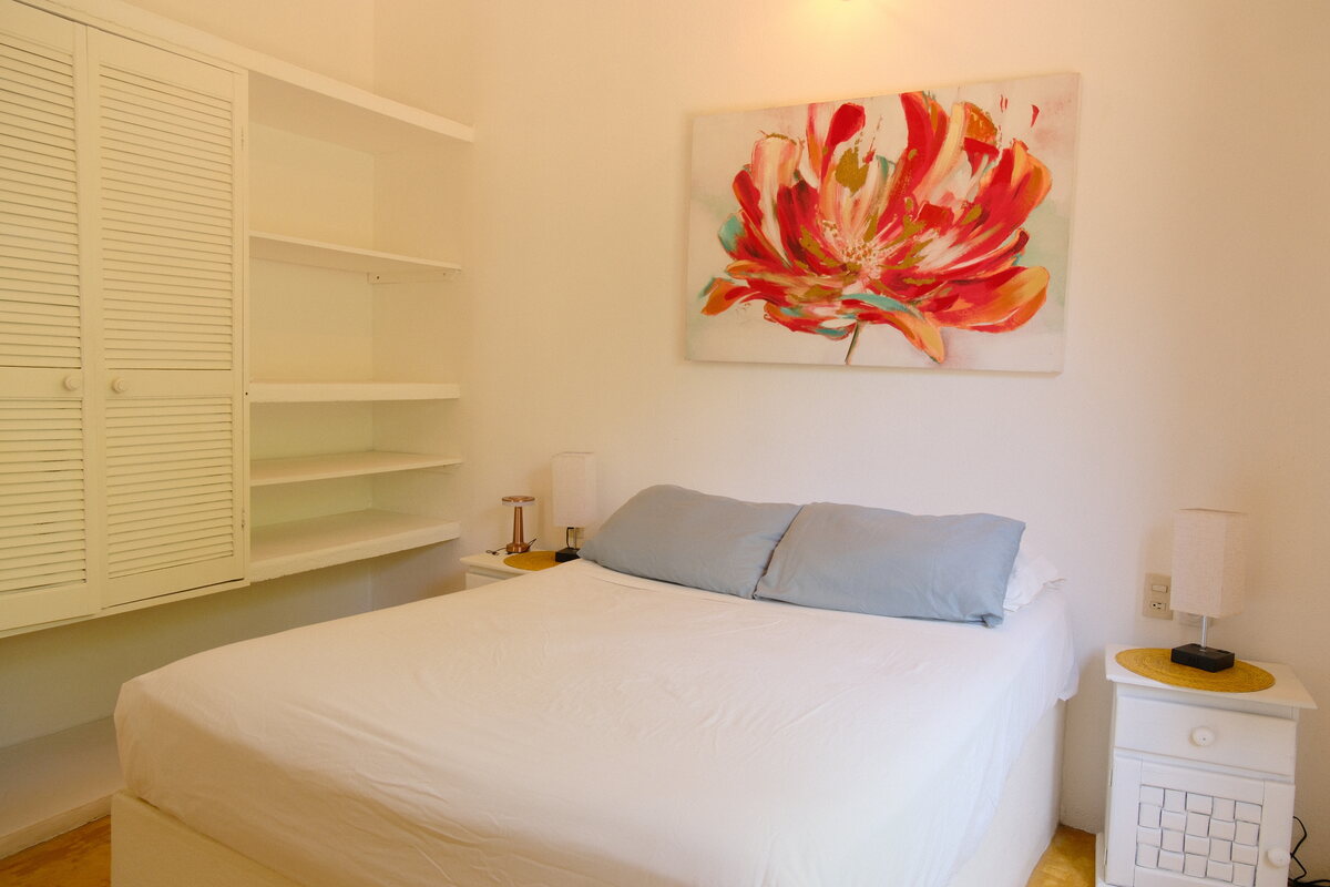 Casa Linda second bedroom — bed with the floral painting and open shelving