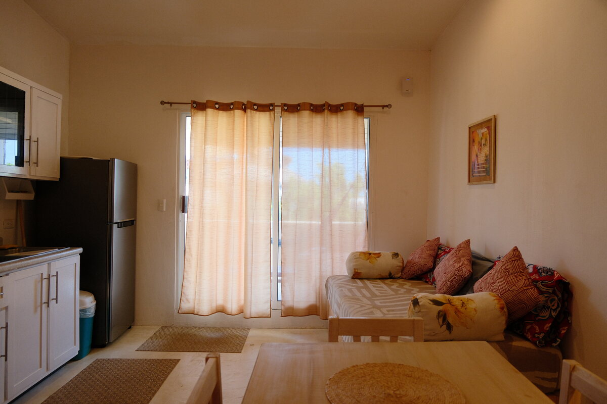 Casa Peach living area — daybed sofa beside curtained glass doors to the terrace