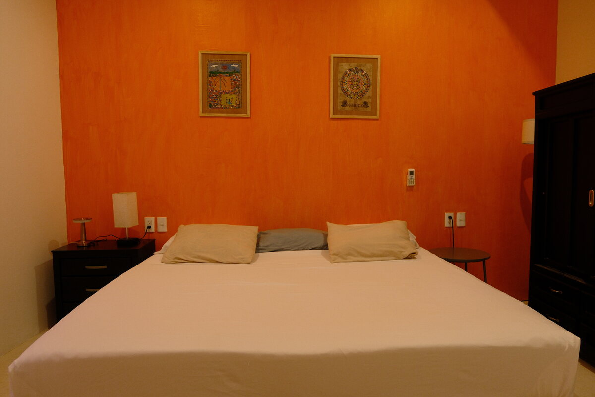 Casa Peach bedroom — king bed against a burnt-orange accent wall with framed prints