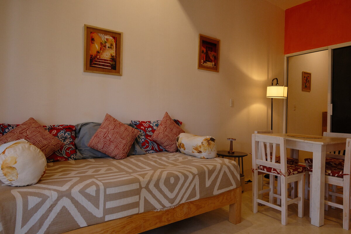 Casa Peach lounge corner — patterned daybed with pillows beside the dining chairs and a reading lamp